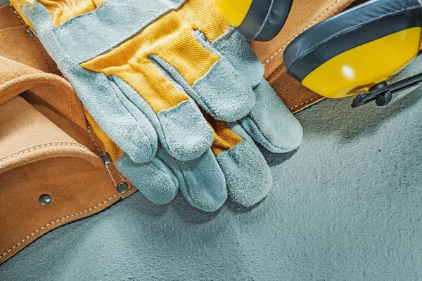 一套皮革工具带防护手套耳罩在混凝土上 — 图库照片