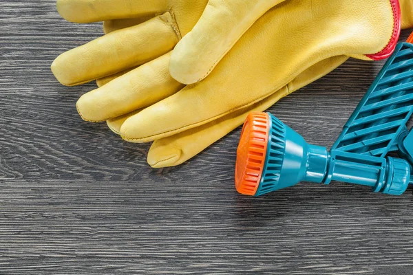 Garden hand spray gun protective gloves on wooden board — Stock Photo, Image
