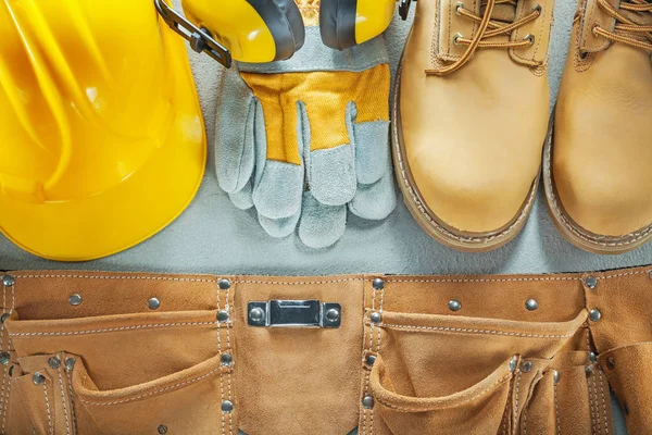 Hard hat tool belt safety gloves boots earmuffs on concrete back — Stock Photo, Image