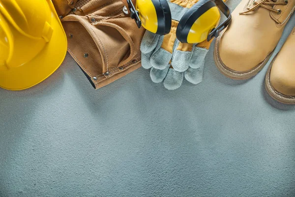 Hard hat tool belt protective gloves boots earmuffs on concrete — Stock Photo, Image