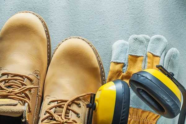 Botas de seguridad de cuero guantes orejeras sobre fondo de hormigón — Foto de Stock