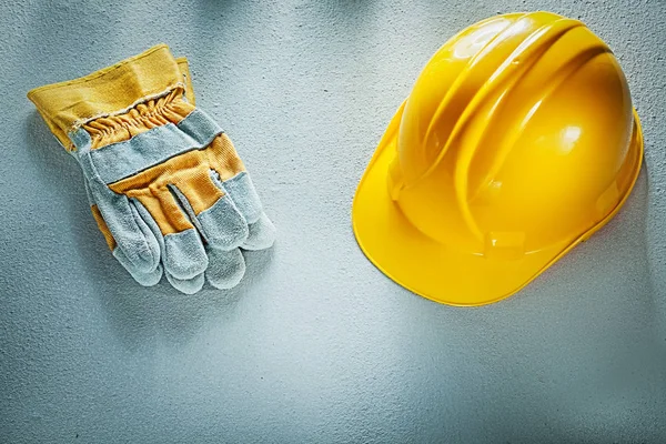 Pair of safety gloves hard hat on concrete background — Stock Photo, Image