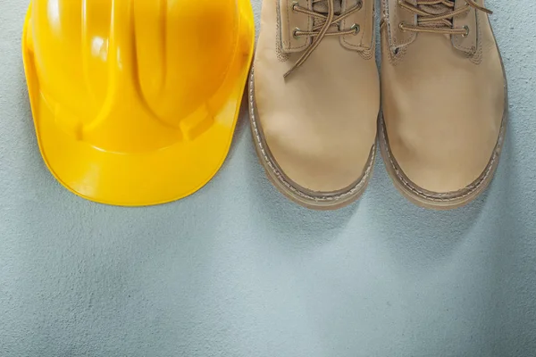 Hard hat pair of leather lace boots on concrete background