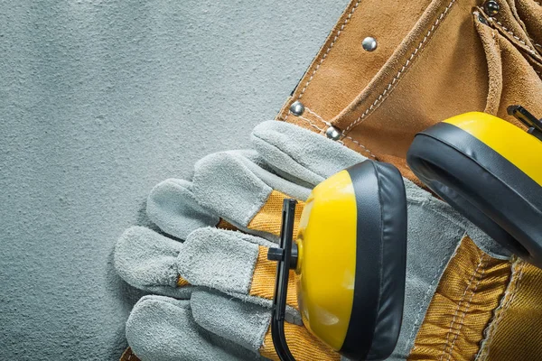 Leather tool belt protective gloves earmuffs on concrete backgro — Stock Photo, Image