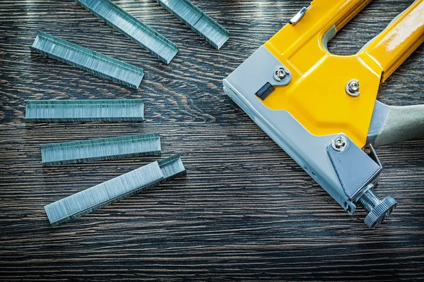 Construction stapler staples on wooden board — Stock Photo, Image