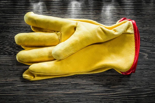 Leather safety gloves on wooden board — Stock Photo, Image