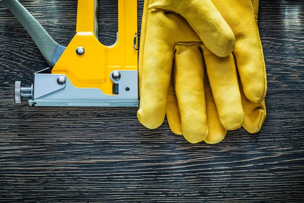 Leather protective gloves construction stapler on wooden board — Stock Photo, Image