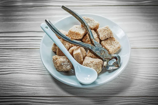 Vintage sugar pliers  and white ceramic spoon in sauser — Stock Photo, Image