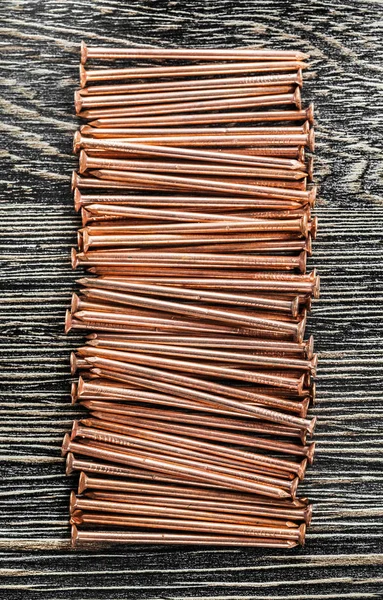 Empilement de clous en cuivre sur une planche en bois — Photo