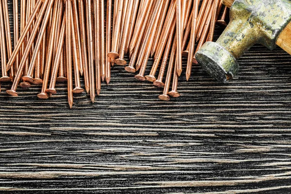 Heap of copper nails claw hammer on wooden board — Stock Photo, Image