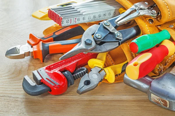 Construction tooling in leather tool belt on wooden board — Stock Photo, Image