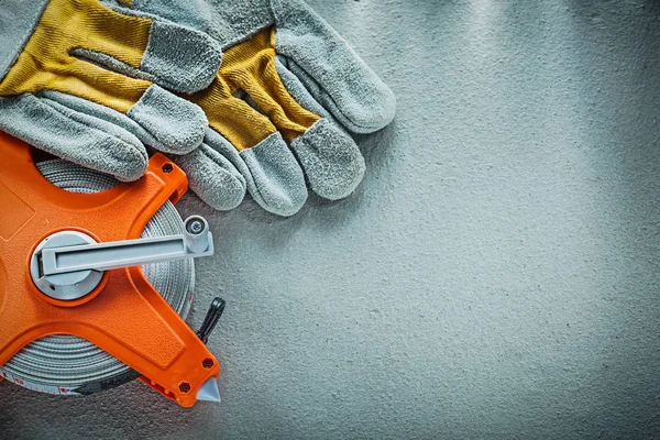 Pair of safety gloves tape measure on concrete background — Stock Photo, Image