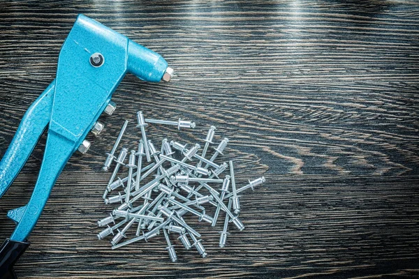 Riveting pliers pile of screws on wooden board — Stock Photo, Image