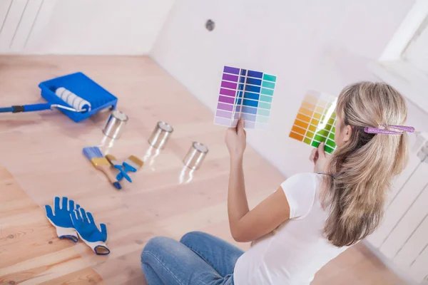 Female sitting on the floor and selecting color for wall with pa — Stock Photo, Image