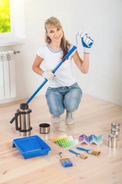 güzel gülümseyen kadın ressam Holding paintroller oturan ve