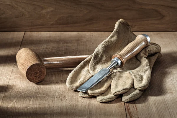 Un mazzuolo rotondo chissel e guanti su fondo legno — Foto Stock