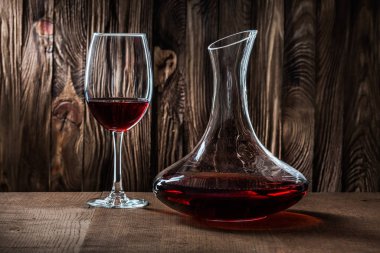 Kaliteli ahşap arka planda kırmızı şaraplı sürahi ve cam.