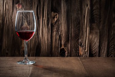 Kopya uzay manzaralı şarap kadehi, üzerinde kırmızı şarap olan eski ahşap bir sırt çantası.