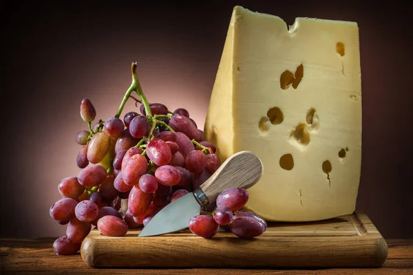 Gran Pedazo Queso Con Uva Rosa Cuchillo Pequeño Sobre Tabla —  Fotos de Stock