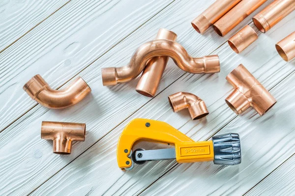 copper pipes and fittings pipecutter on white boards