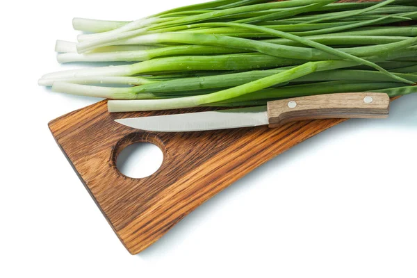 隔离的木制刨花板上的绿色葱茎和菜刀 — 图库照片