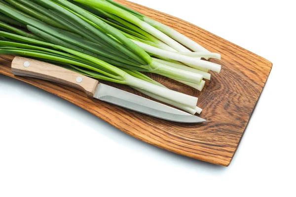 绿色的春天洋葱葱柄与菜刀在木制切菜板上隔离的白色 — 图库照片