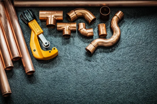 plumbing concept copper pipes pipe cutter and fittings on black background