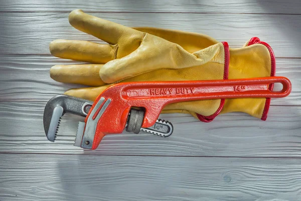 水暖工猴子扳手和黄色皮革工作手套在老式的白色涂漆木板上 图库照片