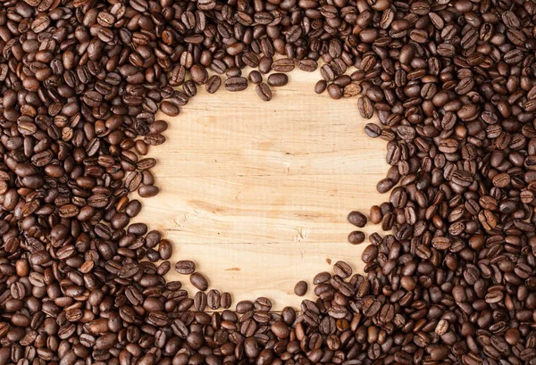 Circle frame of coffee beans on wooden table — Stock Photo, Image