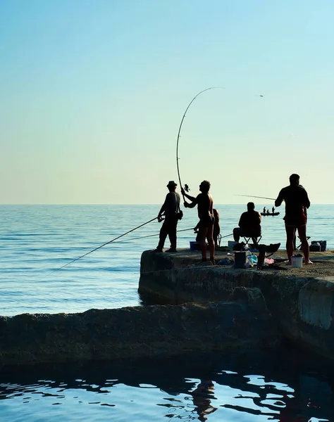 Группа рыбаков на пирсе на закате . — стоковое фото