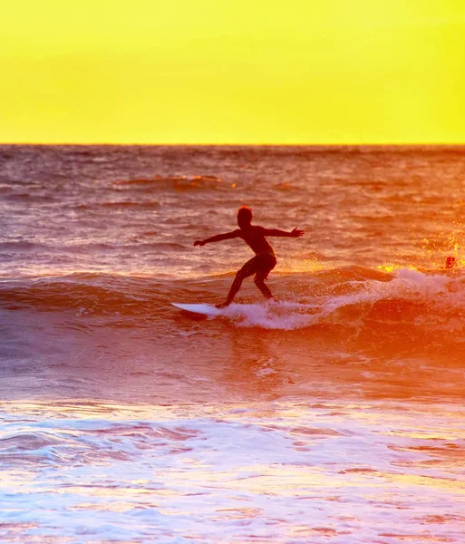 Surfista surfa no oceano ao pôr-do-sol — Fotografia de Stock