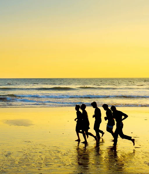 Люди бегут по океанскому пляжу — стоковое фото