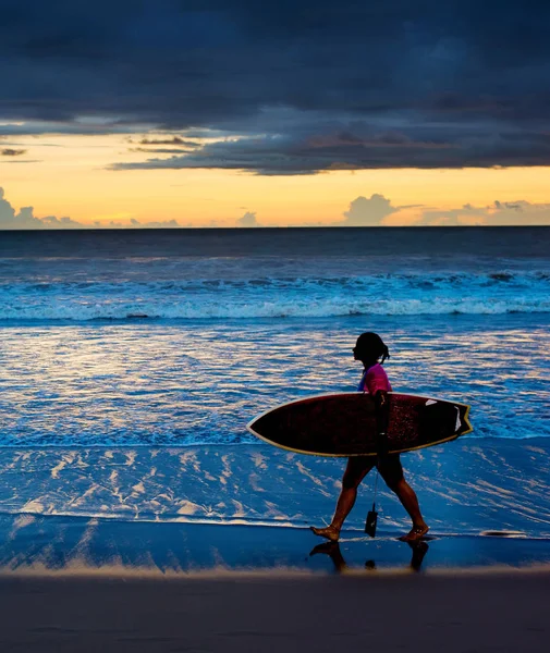 Surfgirl 夕暮れサーフボードとビーチの上を歩いてします バリ島 — ストック写真
