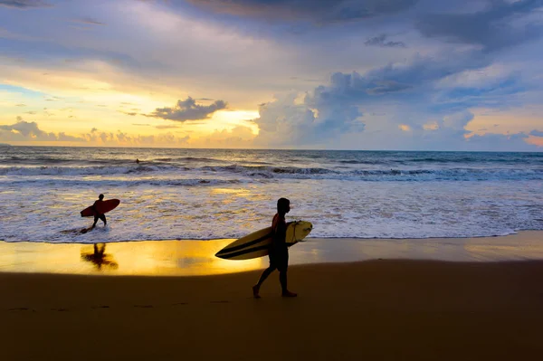 日落时分 两个冲浪者带着冲浪板在海边漫步 巴厘岛 印度尼西亚 — 图库照片