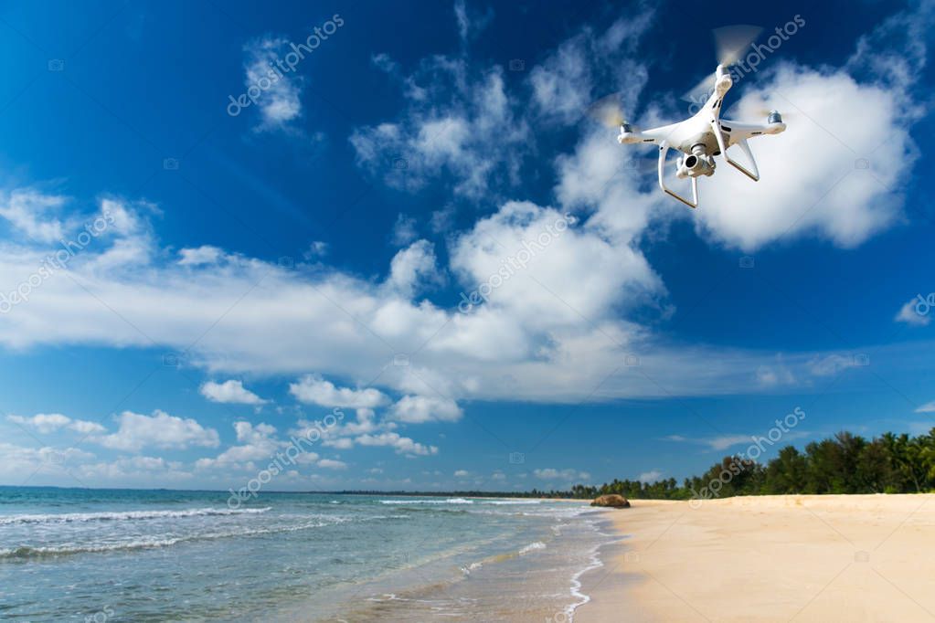 Drone flying over sea. white drone hovering in a bright blue sky. New technology in the aero photo shooting.