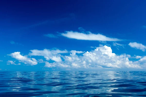 Wolken am blauen Himmel über ruhiger See — Stockfoto