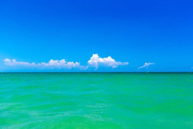 Bulutlar mavi gökyüzünde sakin denizin üzerinde güneş ışığı yansımasıyla