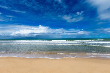 Dalgalı deniz ve mavi gökyüzü ile tropikal plaj 