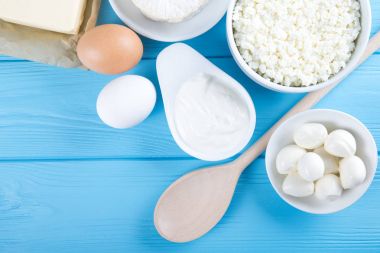 Süt ürünleri mavi ahşap masa üzerinde. Ekşi krema, süt, peynir, yumurta ve tereyağı. Kopya alanı ile Üstten Görünüm