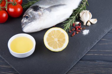 Dorado çiğ balık pişirme ve malzemeler. Dorado, limon, domates, otlar ve baharatlar. Ahşap tabl üzerinde Üstten Görünüm