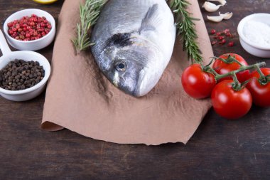 Dorado çiğ balık pişirme ve malzemeler. Dorado, limon, domates, otlar ve baharatlar. Ahşap tabl üzerinde Üstten Görünüm
