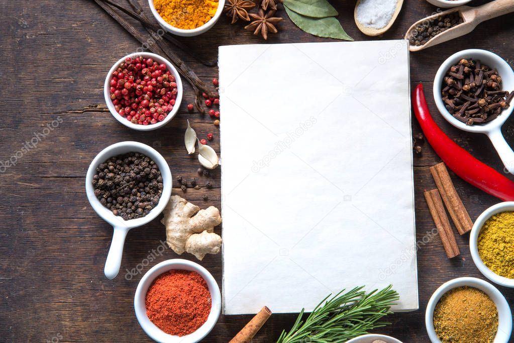 Open recipe book with fresh herbs and spices on wooden background