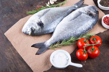 Dorado çiğ balık pişirme ve malzemeler. Dorado, limon, domates, otlar ve baharatlar. Ahşap masa üzerinde Üstten Görünüm