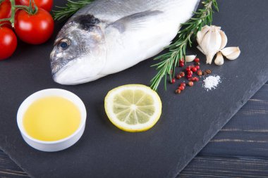 Dorado çiğ balık pişirme ve malzemeler. Dorado, limon, domates, otlar ve baharatlar. Ahşap masa üzerinde Üstten Görünüm