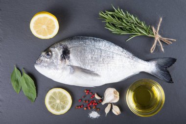 Dorado çiğ balık pişirme ve malzemeler. Dorado, limon, domates, otlar ve baharatlar. Ahşap masa üzerinde Üstten Görünüm