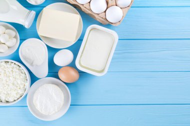 Süt ürünleri mavi ahşap masa üzerinde. Ekşi krema, süt, peynir, yumurta ve tereyağı. Kopya alanı ile Üstten Görünüm