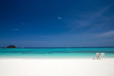 beyaz kumlu plaj ve deniz ile tropikal Maldivler Adası'nda iki güverte sandalyeleri