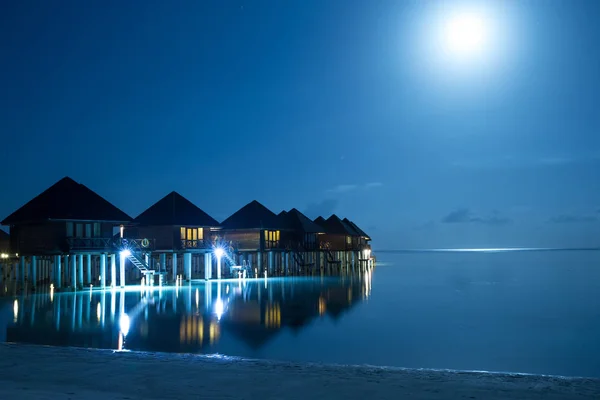 luxury water villas resort and wooden pier on Maldives island at nighttime