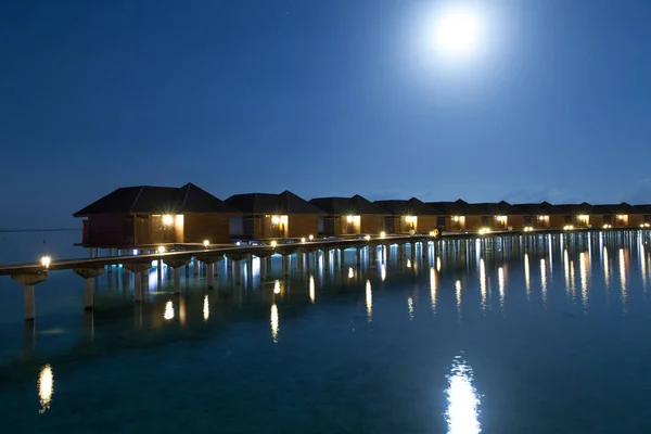 luxury water villas resort and wooden pier on Maldives island at nighttime