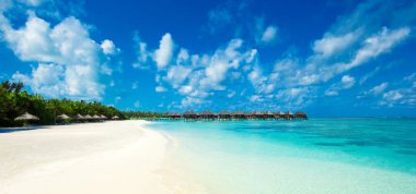 Beyaz kumlu sahil, turkuaz okyanus suyu ve güneşli bir günde bulutlu mavi gökyüzü. Yaz tatili için doğal bir geçmiş. Panoramik görünüm.